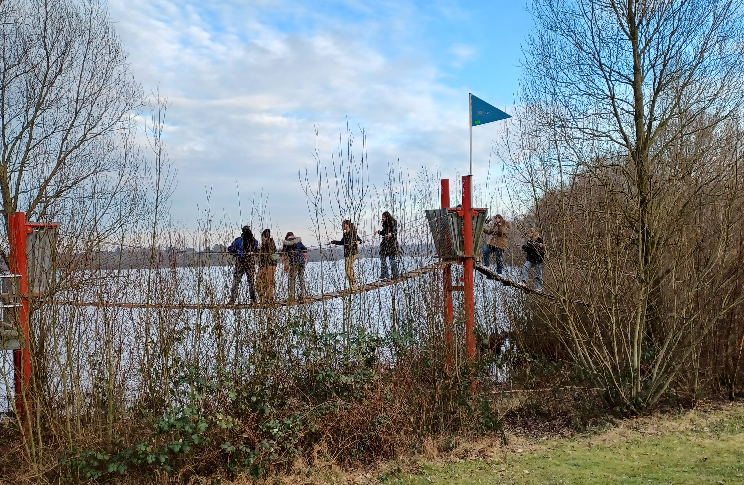 Glaubenskurse Mehrere Personen auf einer Hängebrücke vor einem See